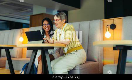 A high school teacher mentoring a student using a tablet, highlighting the use of technology in education and personalized learning in a modern school Stock Photo