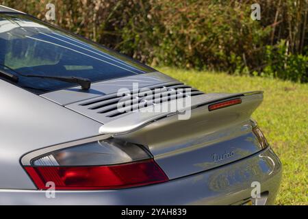 Detail of a silver porsche 911 turbo parked on grass with its spoiler and taillight visible Stock Photo