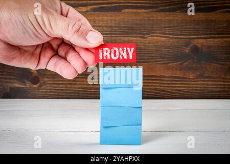 Irony Concept. Blue wooden blocks in a pile on a white wooden table. Stock Photo
