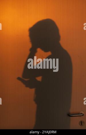 11.12.2023, China, Hongkong, Hong Kong - Silhouette: youth looking shocked at his smartphone. 00S231211D386CAROEX.JPG [MODEL RELEASE: YES, PROPERTY RE Stock Photo
