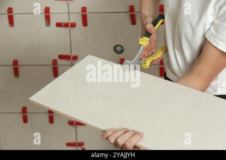 Worker cutting ceramic tile with ceramic tile cutter nipper. DIY home improvement project. Stock Photo