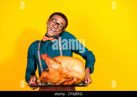 Photo of classy young man communicate phone hold roasted thanksgiving turkey isolated on yellow color background Stock Photo