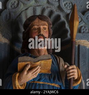 Saint Matthew the Apostle and Evangelist, sculpted in wood in 1721.  Head and shoulders of one of 12 polychrome apostle statues flanking the entrance to a Breton church, L’Eglise Saint Sauveur in Le Faou, Finistère, Brittany, France. Matthew holds a spear, symbol of his martyrdom, rather than a pen, symbol of his evangelism. Stock Photo