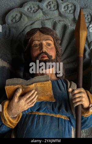 Saint Matthew the Apostle and Evangelist holds a spear, symbol of his martyrdom, rather than a pen, symbol of his evangelism.  Head and shoulders of one of 12 polychrome apostle statues, sculpted in wood in 1721, that flank the entrance to a Breton church, L’Eglise Saint Sauveur in Le Faou, Finistère, Brittany, France.  The statues  have recently been restored and repainted. Stock Photo