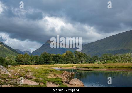 The waters of Loch Etive reflecting the surrounding mountains, with the snow capped peak of Ben Cruachan in the distance, Argyll and Bute, Scotland. Stock Photo