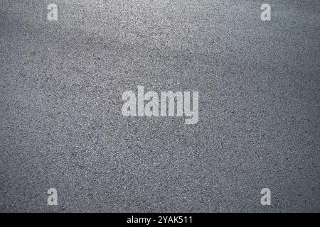 A close-up view of a gray, grainy surface with a textured appearance, resembling rough concrete or asphalt. The image shows a uniform, speckled patter Stock Photo