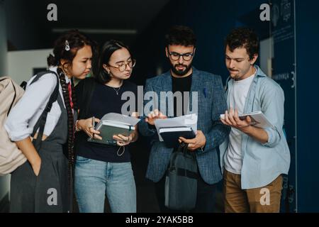 Students engaging in discussion with professor in hallway Stock Photo