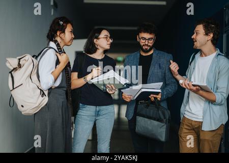Students engaging with a professor in university hallway discussion Stock Photo
