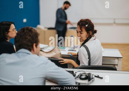 Students engaging in classroom tasks with attentive professor support Stock Photo