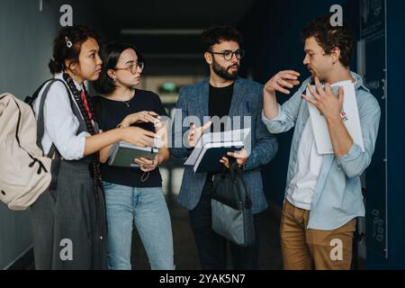 Students engaged in discussion with professor in university hallway Stock Photo