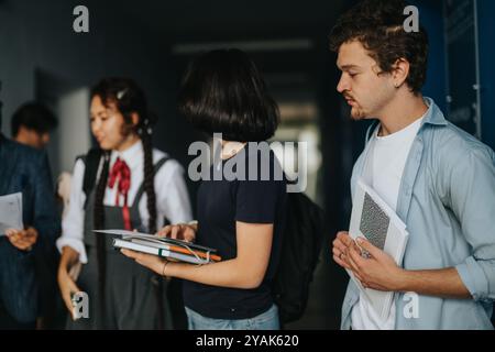 Students engaging with professor in a hallway discussion Stock Photo
