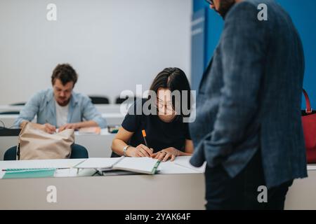 Professor assisting students during an engaging classroom session Stock Photo