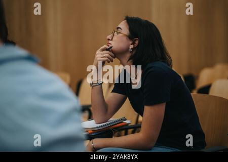 Thoughtful student engaged in a university lecture setting Stock Photo