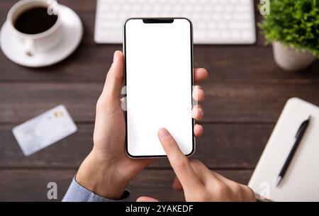 Man using blank smartphone on workplace desk Stock Photo