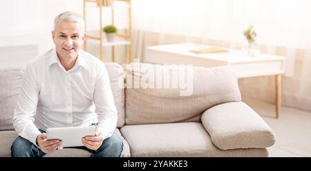 Senior man using digital tablet looking at camera Stock Photo