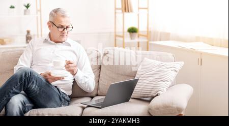 Elderly Man Using Laptop Computer And Having Coffee Stock Photo