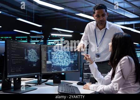 Teamworking professionals working on PC in data center with artificial intelligence tech. Coworkers doing brainstorming, solving tasks in server hub storing data used for deep learning Stock Photo