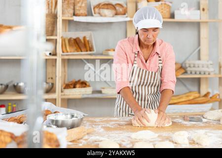Elderly female baker working diligently in a bakery Stock Photo