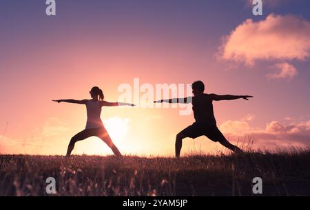 Couple doing yoga in the park at sunset. Stock Photo