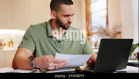 Home, man and reading with document on laptop for tax, invoice and bank statement with financial problems. Male person, house and serious with Stock Photo