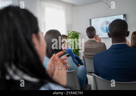 Diverse group of professionals attending a business presentation or training seminar. View from behind showing attentive audience and SWOT analysis on Stock Photo