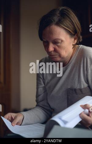 Female freelancer doing paperwork in home office interior, selective focus Stock Photo
