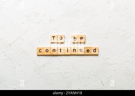 To be continued word written on wood block. To be continued text on cement table for your desing, concept. Stock Photo