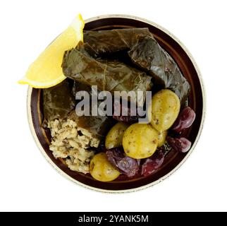 Stuffed vine leaves filled with rice and herbs and mixed Mediterranean olives on a small plate isolated on a white background Stock Photo