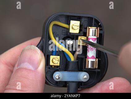 Person wiring a black British three pin electrical plug Stock Photo
