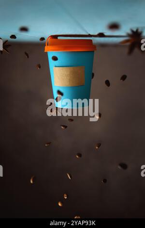 conceptual creative photography of coffee in a takeaway blue mockup cup, with copy space. inverted composition, falling coffee beans Stock Photo