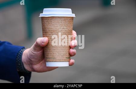 Male hand holding a take away cup of coffee. Stock Photo