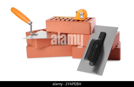 Red bricks, trowel, measuring tape and putty knife isolated on white. Building material and construction tools Stock Photo