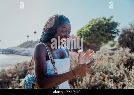A woman is holding a cell phone and smiling while receiving a message, surprised facial expression Stock Photo
