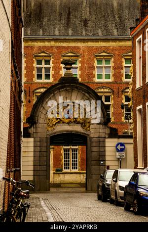 Arched stone gate with bas-relief cherub sculpture and a heraldic shield  in Bruges, Belgium. Stock Photo