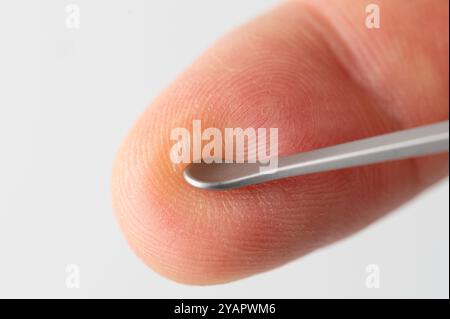 Metal medical tool pinch blister on finger macro close up view Stock Photo