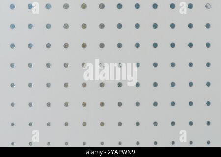 Textured white background features metallic dots arranged in precise grid pattern, showcasing interesting design. Stock Photo