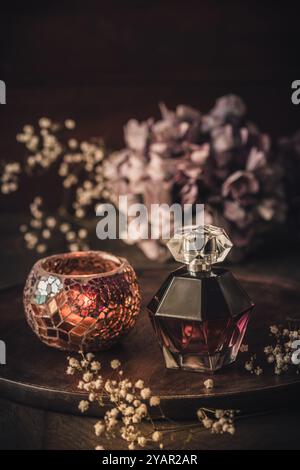 Perfume bottle with decoration on wooden tray, vertical, dark colors Stock Photo