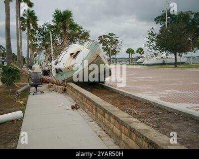 Green and white Beached sailboat on sidewalk after storm surge at Gulfport, Florida. Boat on its side with houses in the background. Washed up Stock Photo