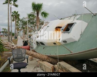 Green and white Beached sailboat on sidewalk after storm surge at Gulfport, Florida. Boat on its side with houses in the background. Washed up Stock Photo