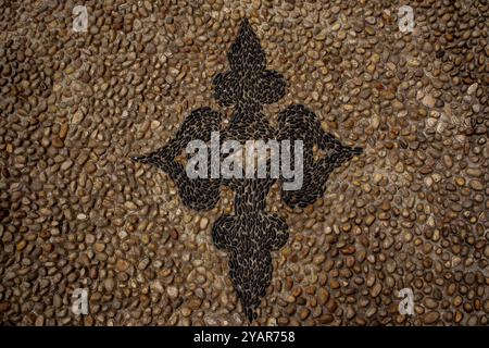 Decorative pebble mosaic on an ancient street. Greek mosaic floor texture top view. A pattern of small stones on the city sidewalk. Patch Paving stone Stock Photo