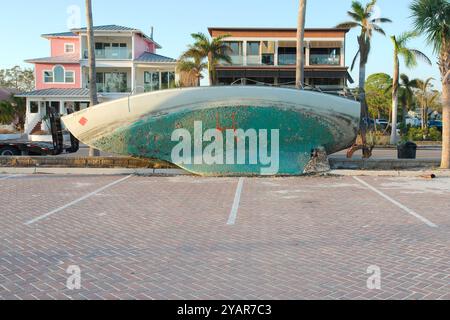 Green and white Beached sailboat on sidewalk after storm surge at Gulfport, Florida. Boat on its side with houses in the background. Washed up Stock Photo