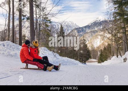 Joyful couple slides on a snow sled through a beautiful snowy forest Stock Photo