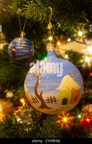 Close up of a painted Christmas bauble hanging on the Christmas tree. Winter scene painted on a Christmas ball. Blue Christmas decoration Stock Photo