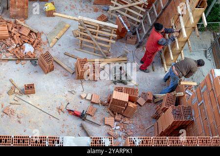 Construction workers are checking the measurement of the wall of the house they built from building blocks. Stock Photo