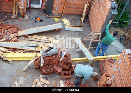 Construction workers are checking the measurement of the wall of the house they built from building blocks. Stock Photo