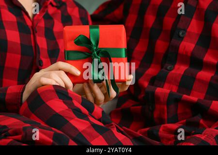 Young couple wearing plaid pajamas with gift, closeup Stock Photo