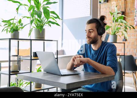Young handsome man in headphones having work video chat using laptop Stock Photo