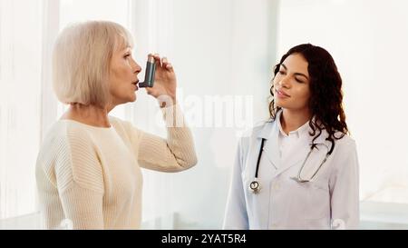 Physician examining mature woman using blue asthma inhaler Stock Photo