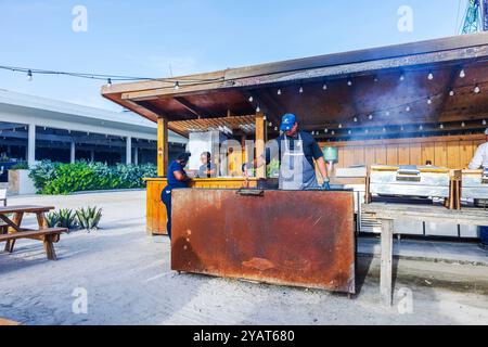 Chef preparing barbecue ribs in an open-air restaurant kitchen with large grill. Stock Photo