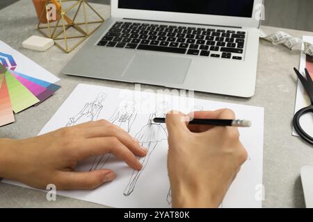 Fashion designer drawing sketch of stylish clothes at gray textured table, closeup Stock Photo